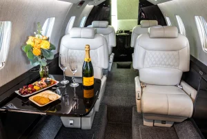 Interior of a private jet. A display of crackers, cheese, and fruit is set up on the tray table.